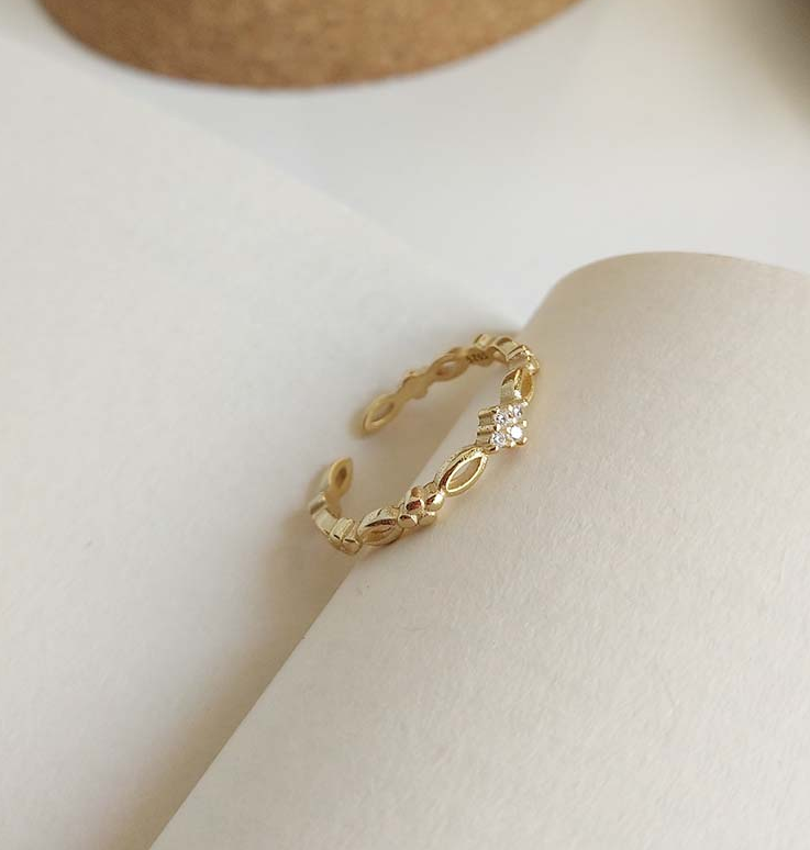Golden Open Ring, a gold-plated openwork band with a small sparkling flower, on a neutral background