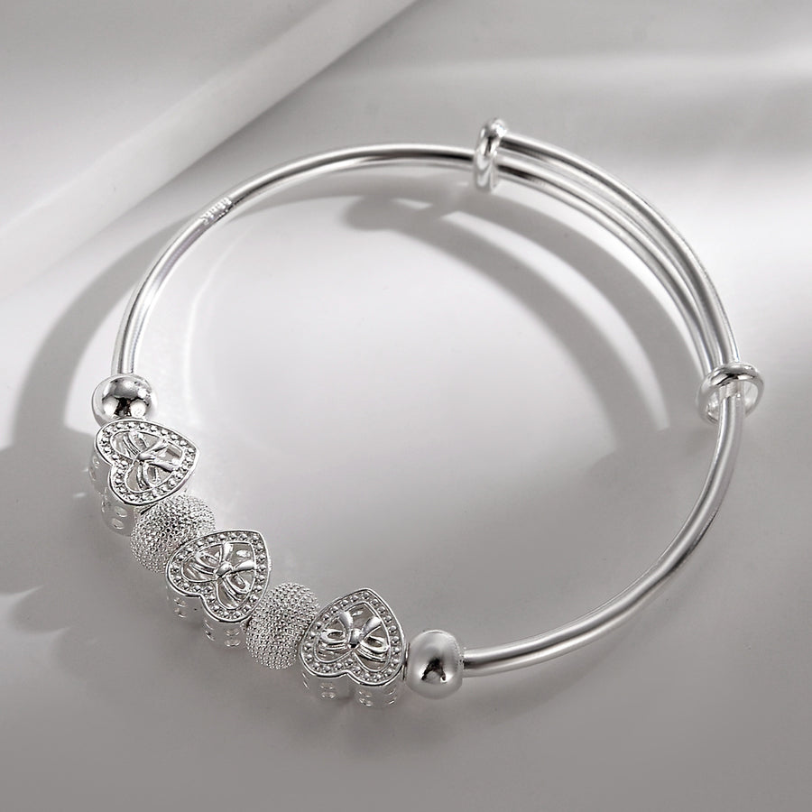 Heart Charm Bangle, a silver-plated adjustable bangle with three openwork heart charms