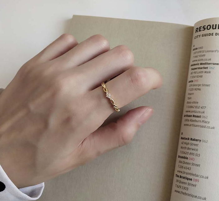 Golden Open Ring worn on a hand resting on an open book