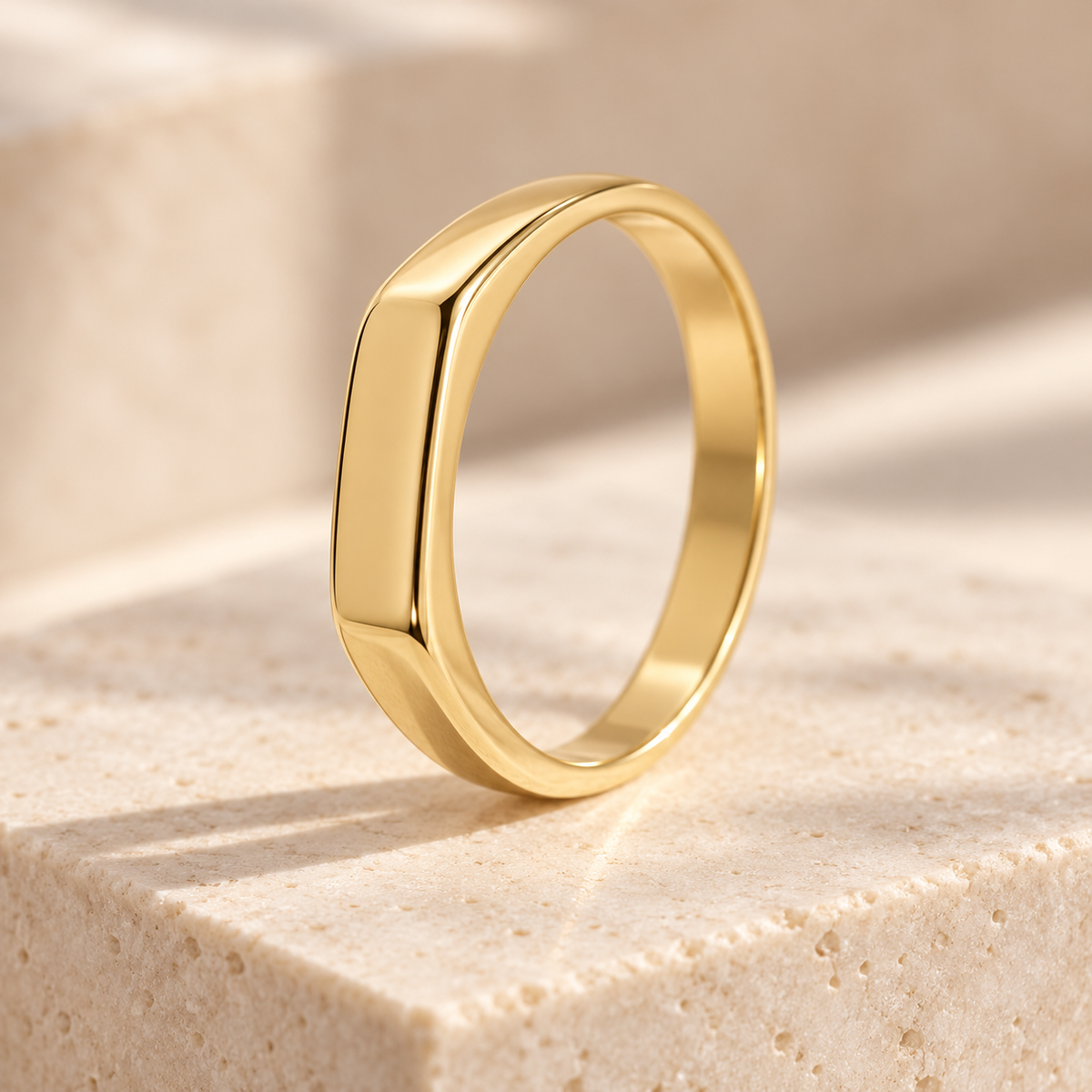 Glow Signet Ring, a slim gold-plated band with a smooth flat signet top, on a stone block